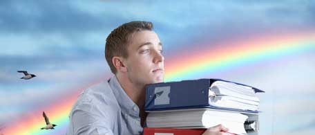A student carries a stack of binders in front of a cloudy sky and a rainbow.